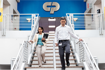Colgate-Palmolive employees going down a flight of stairs with a Colgate-Palmolive logo behind them on a blue wall.