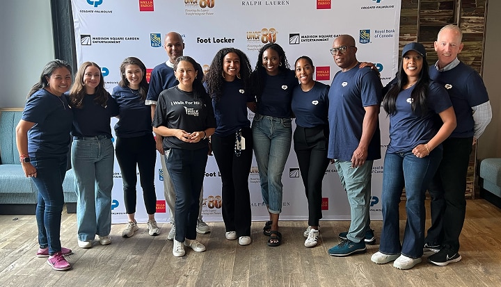 Group of people at the "United Negro College Fund" event, posing for a picture in front of a wall of sponsor logos. 