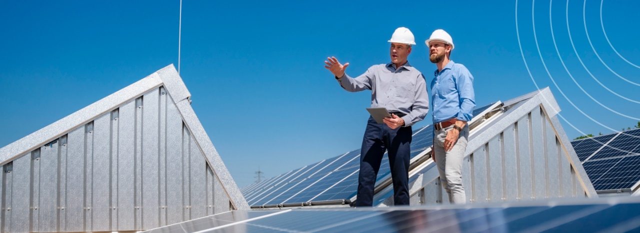 Two men talking while wearing hard hats in the middle of a solar farm.