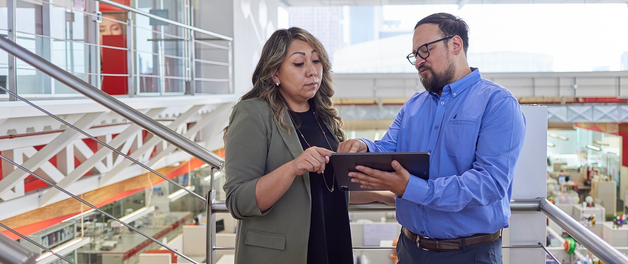 Woman and man talking over efforts to drive sustainability across product lines at a factory.
