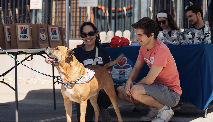 Group of people at a Hill's Pet Nutrition event as they smile at a dog.