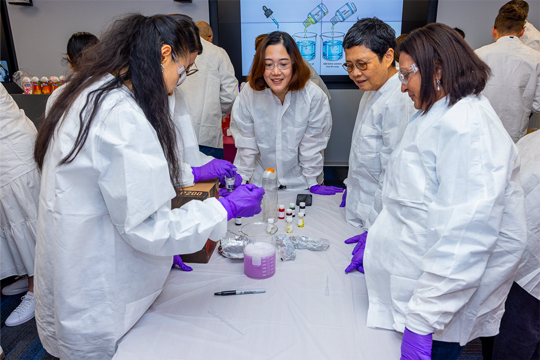 Employees in lab gear formulate body wash.