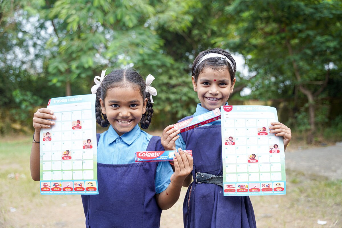 Two girls holding toothpaste and flyer