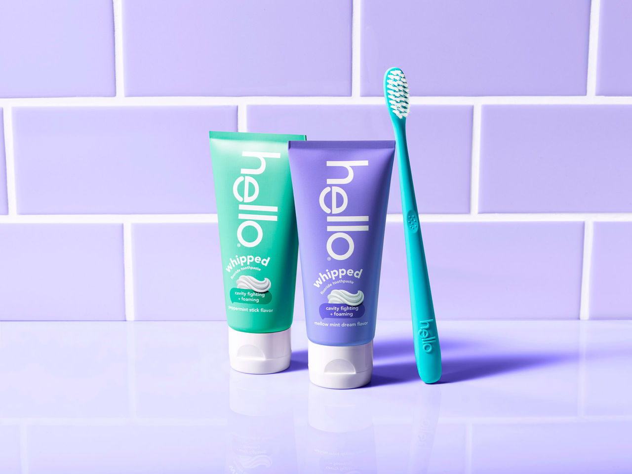 Two tubes of hello Whipped toothpaste and brush with hello logo.