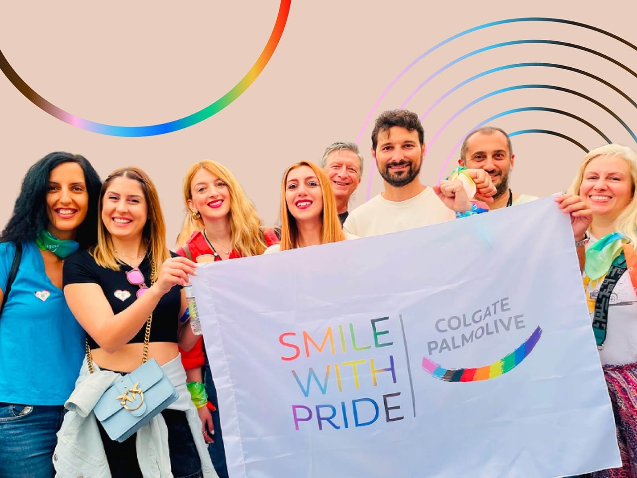 Group of people hold up a smile with pride banner
