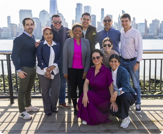 Group of Colgate-Palmolive employees smiling in front of scenic cityscape, representing deep company culture.