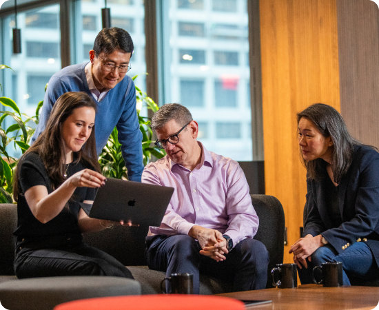 Group of people looking at a computer, representing innovation and ongoing growth.