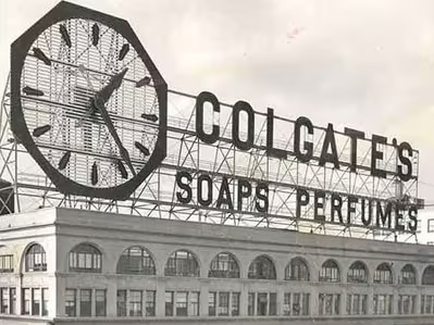 Historic Colgate Clock sign from the 1900s on a building with a sign that reads Colgate's Soaps Perfumes.