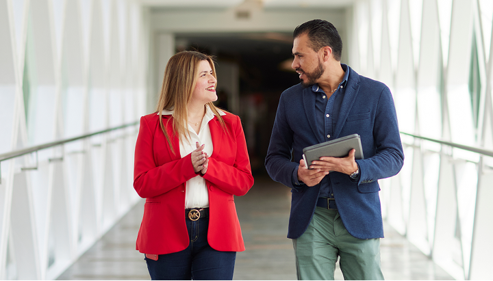 Two Colgate employees having conversation while walking through modern office hallway, showcasing culture.