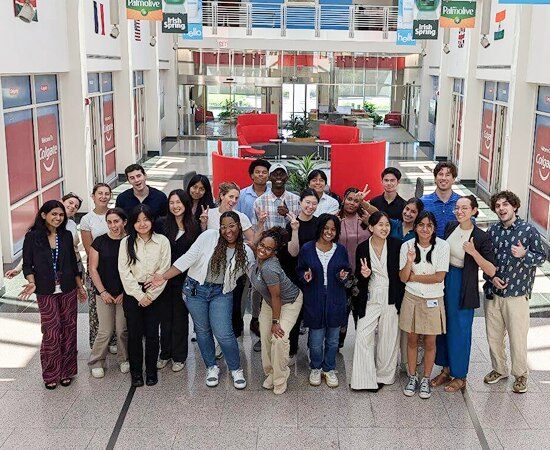 Colgate summer internship program participants posing for a group photo in a bright hallway.