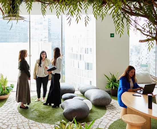 Employees collaborating and working in a modern office space with lush, natural decorations.