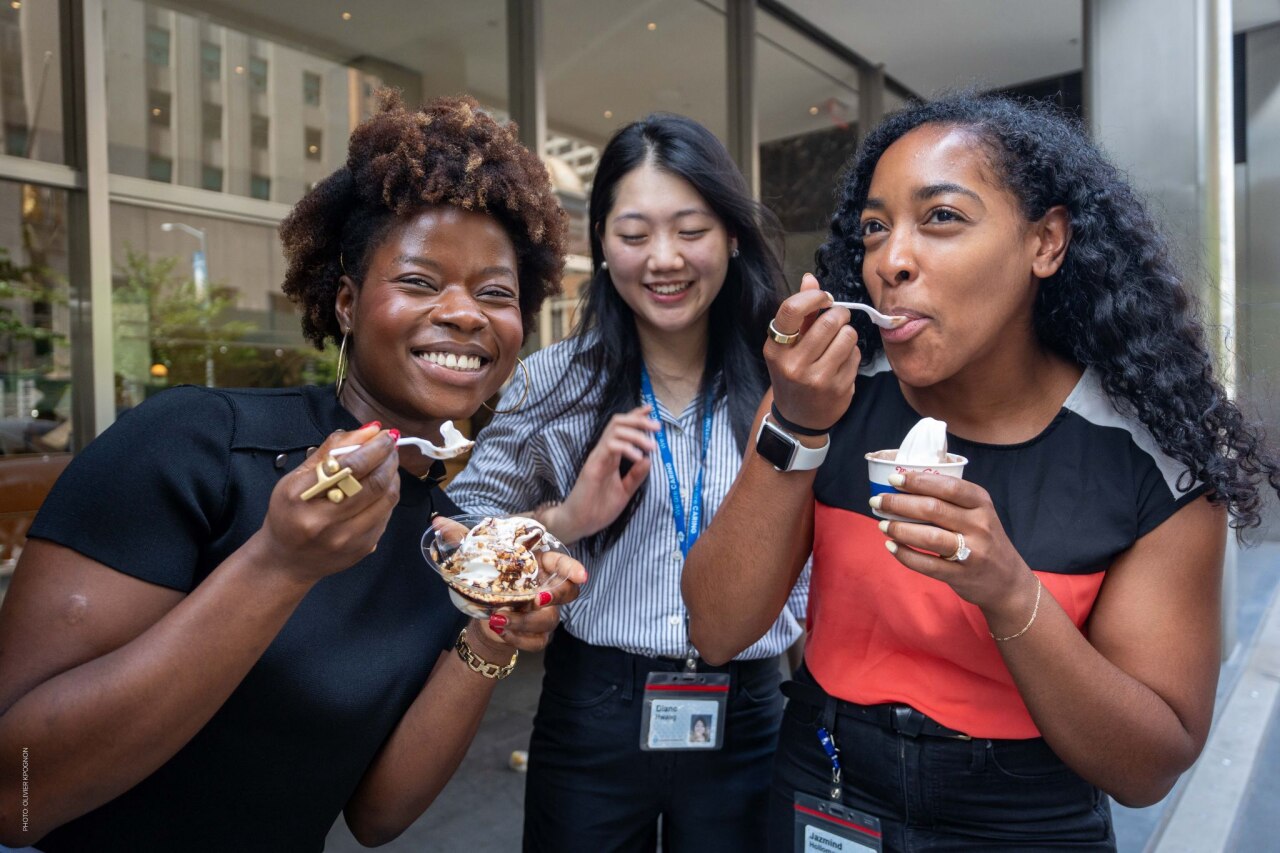Three Colgate-Palmolive employees enjoying ice cream desserts together during a company event.